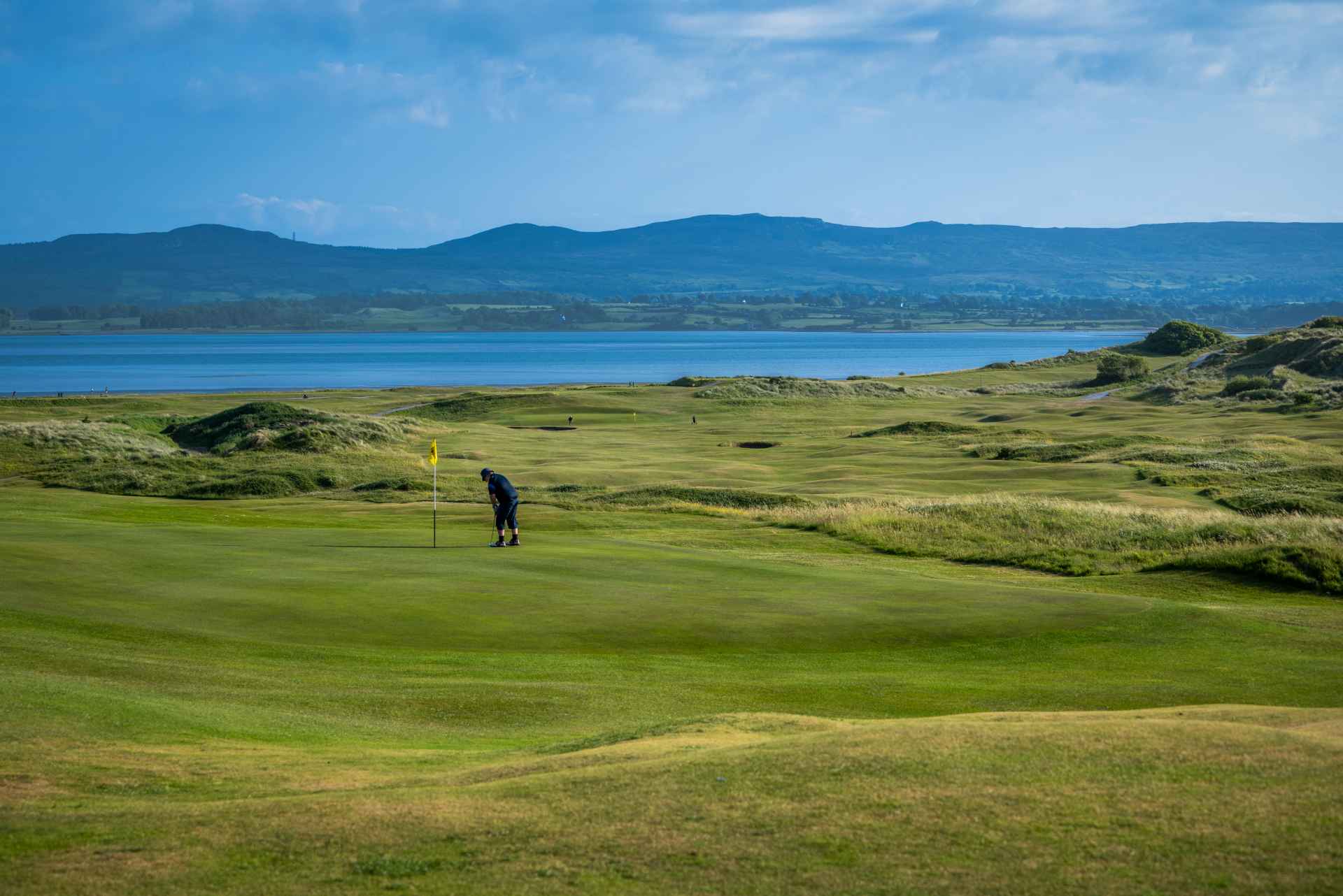 Hole 18 - Bustard’s Lodge - up close of green with a golfer on it putting a ball